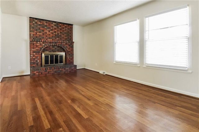 unfurnished living room with dark wood-type flooring and a fireplace