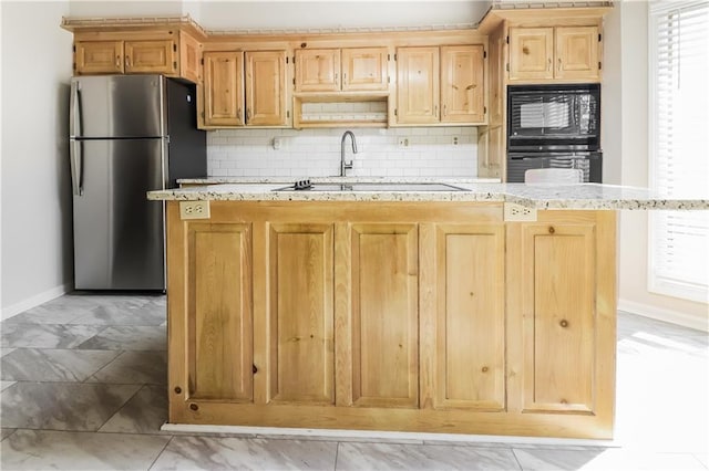 kitchen featuring light brown cabinetry, sink, tasteful backsplash, light stone countertops, and black appliances