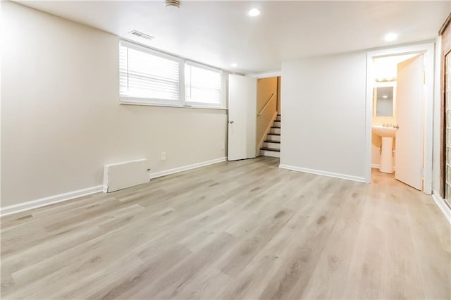 basement featuring sink and light hardwood / wood-style floors