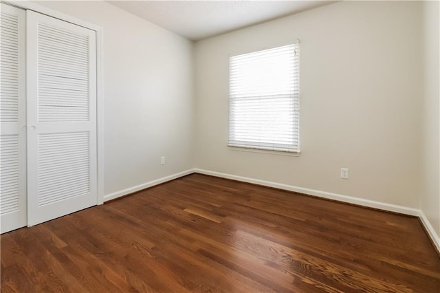 unfurnished bedroom with dark hardwood / wood-style floors and a closet