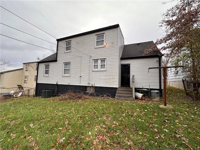 back of house with cooling unit and a lawn