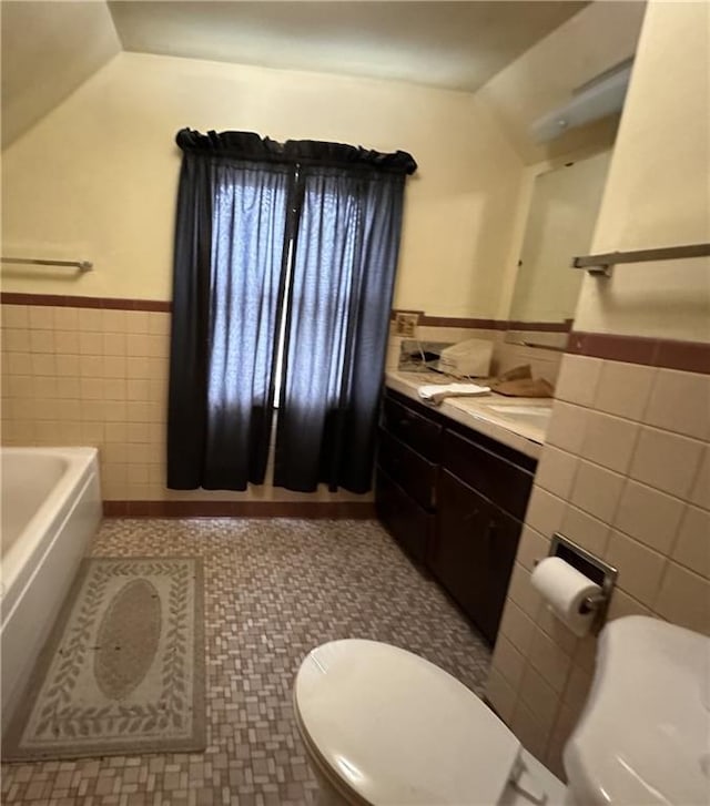 bathroom featuring tile patterned floors, lofted ceiling, tile walls, vanity, and a washtub