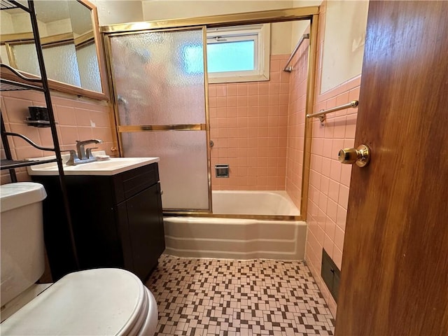 full bathroom with enclosed tub / shower combo, vanity, toilet, and tile walls