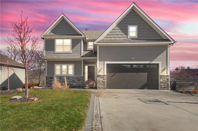 view of front of house featuring a front yard, stone siding, driveway, and an attached garage