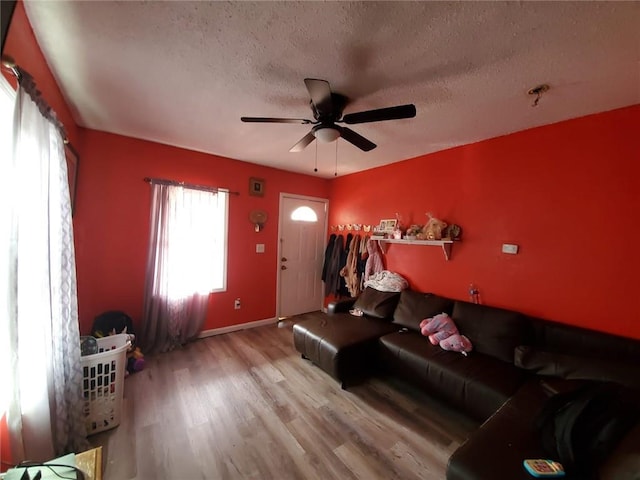 living room with ceiling fan, light hardwood / wood-style floors, and a textured ceiling