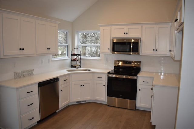 kitchen featuring dark wood-type flooring, lofted ceiling, sink, stainless steel appliances, and white cabinets