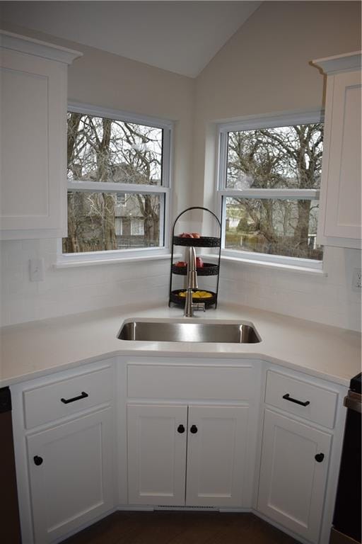 kitchen featuring lofted ceiling, decorative backsplash, and white cabinets