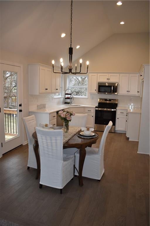 dining space with high vaulted ceiling, dark hardwood / wood-style floors, sink, and a notable chandelier