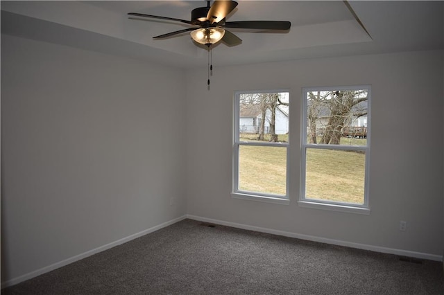 spare room with ceiling fan, a tray ceiling, a healthy amount of sunlight, and carpet