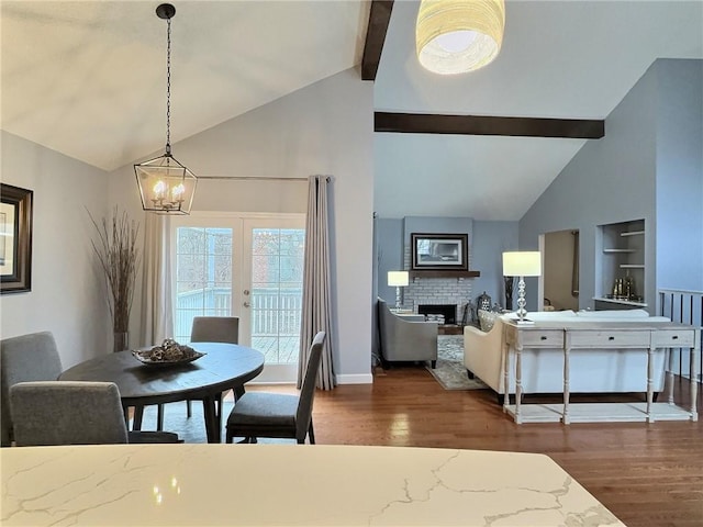 dining area with dark hardwood / wood-style flooring, a notable chandelier, a fireplace, and lofted ceiling with beams