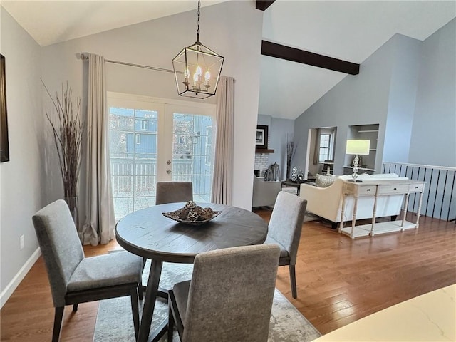 dining space with an inviting chandelier, hardwood / wood-style flooring, high vaulted ceiling, and french doors