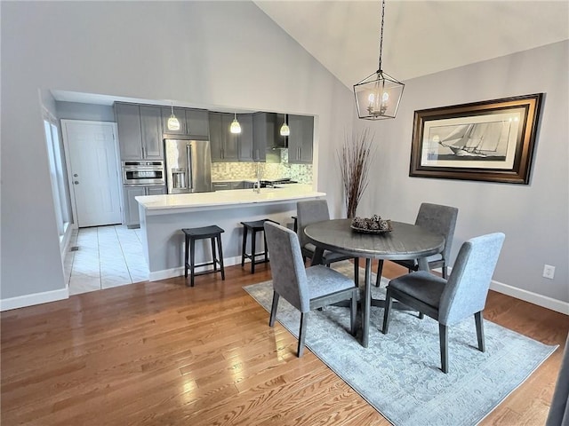 dining room featuring a notable chandelier, light hardwood / wood-style flooring, and high vaulted ceiling