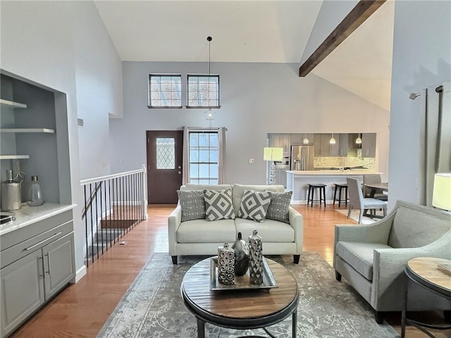 living room featuring high vaulted ceiling, beam ceiling, a chandelier, and hardwood / wood-style floors