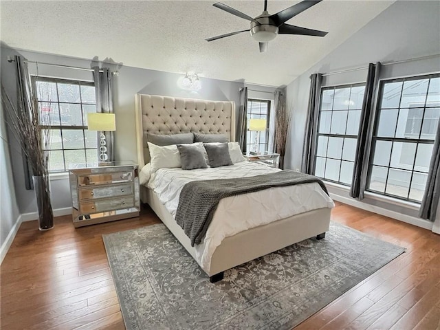 bedroom with ceiling fan, lofted ceiling, dark hardwood / wood-style floors, and a textured ceiling