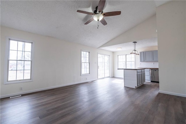 unfurnished living room featuring vaulted ceiling, plenty of natural light, and dark hardwood / wood-style flooring