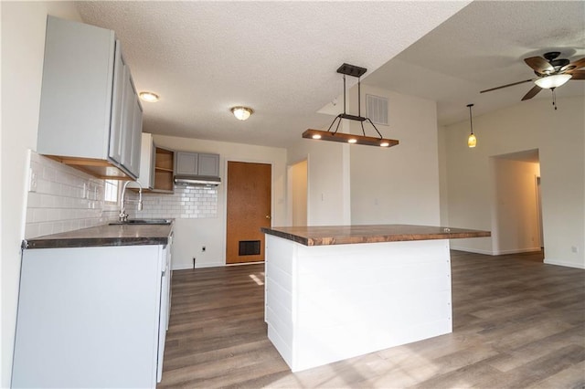 kitchen with sink, decorative light fixtures, dark hardwood / wood-style floors, and a kitchen island