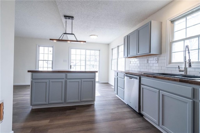 kitchen with sink, stainless steel dishwasher, dark hardwood / wood-style floors, gray cabinets, and pendant lighting