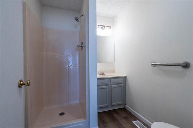 bathroom featuring vanity, wood-type flooring, a shower, a textured ceiling, and toilet