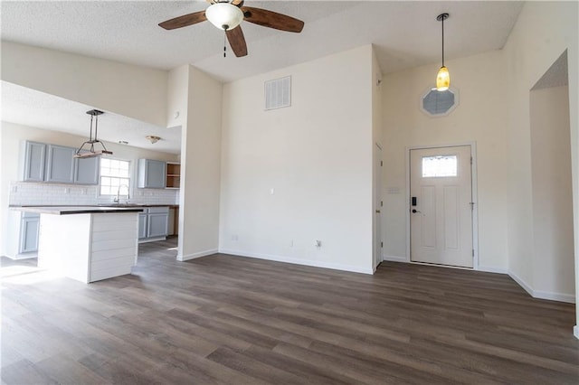 entrance foyer with dark wood-type flooring, ceiling fan, and a high ceiling