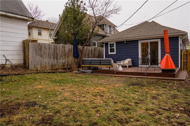 back of property with a deck and a lawn