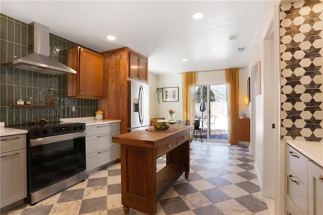 kitchen featuring tasteful backsplash, wall chimney range hood, electric range, and stainless steel fridge with ice dispenser