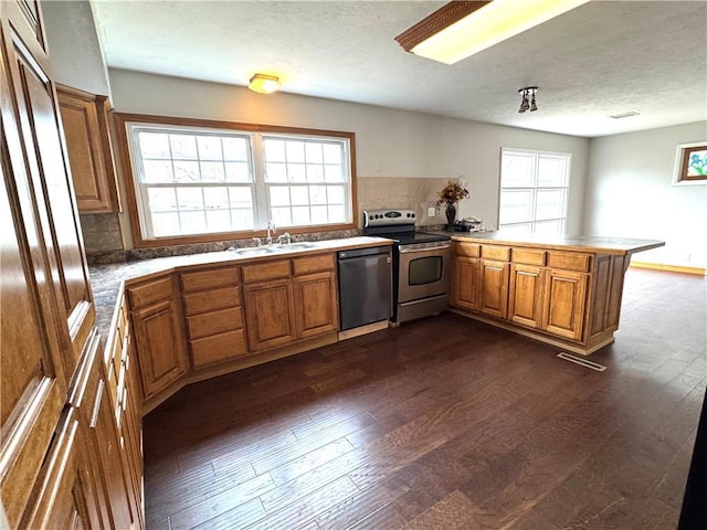 kitchen featuring sink, stainless steel range with electric stovetop, dark hardwood / wood-style flooring, black dishwasher, and kitchen peninsula