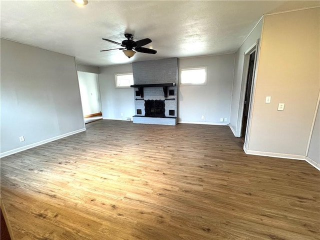 unfurnished living room with dark hardwood / wood-style flooring, a fireplace, and ceiling fan