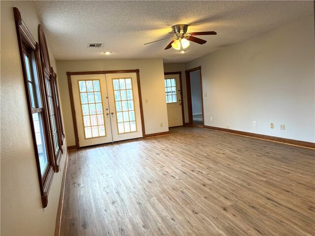 unfurnished room with french doors, ceiling fan, light hardwood / wood-style floors, and a textured ceiling