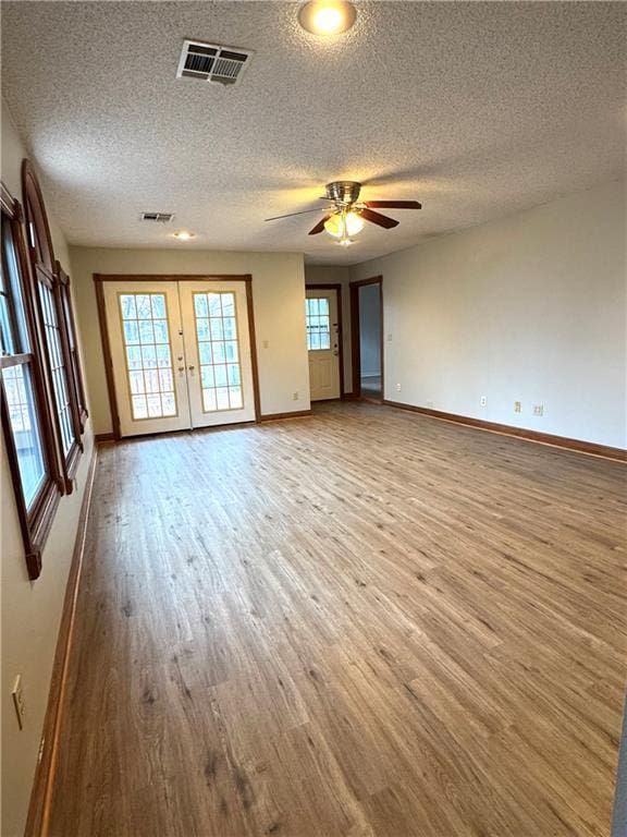 empty room with a textured ceiling, wood-type flooring, and ceiling fan