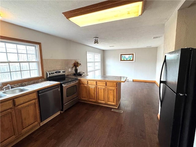 kitchen with a healthy amount of sunlight, kitchen peninsula, sink, and black appliances