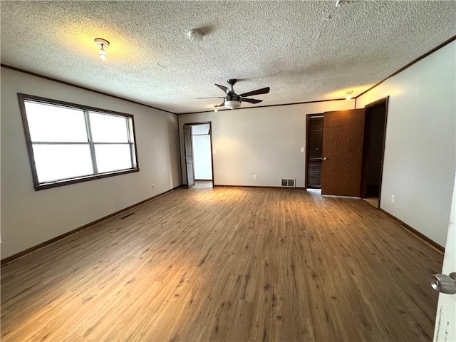 empty room with hardwood / wood-style flooring, ceiling fan, crown molding, and a textured ceiling