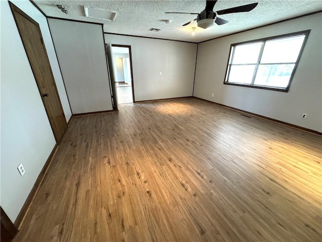 empty room featuring crown molding, ceiling fan, a textured ceiling, and light hardwood / wood-style floors