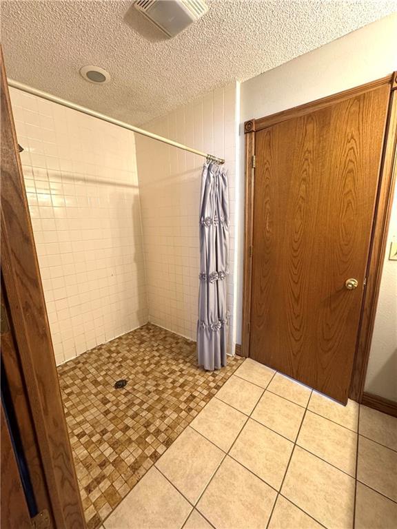 bathroom featuring walk in shower, tile patterned flooring, and a textured ceiling