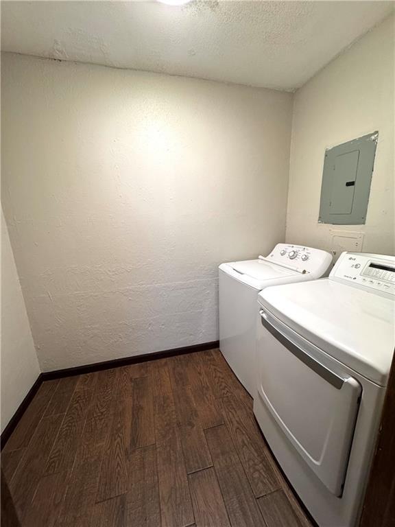 laundry area with washer and dryer, electric panel, dark hardwood / wood-style floors, and a textured ceiling