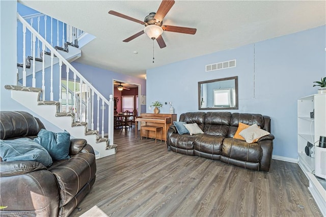 living area with stairs, visible vents, wood finished floors, and a ceiling fan