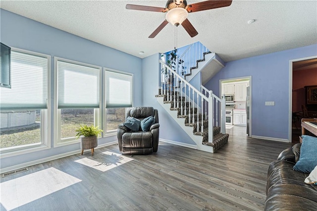 living area with stairs, wood finished floors, baseboards, and ceiling fan