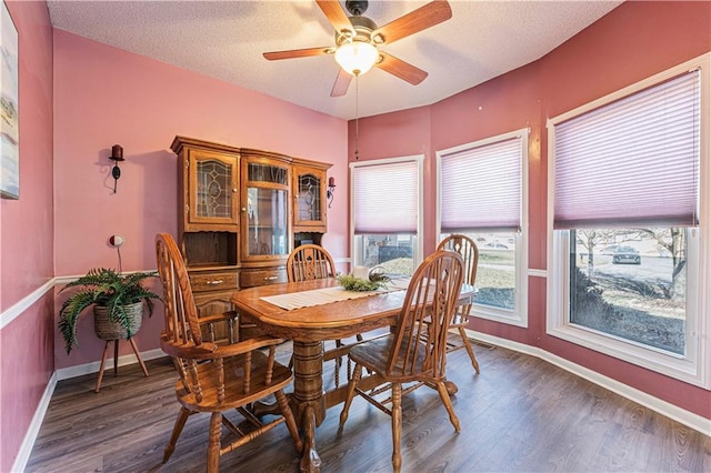 dining space featuring baseboards, a textured ceiling, dark wood finished floors, and a ceiling fan