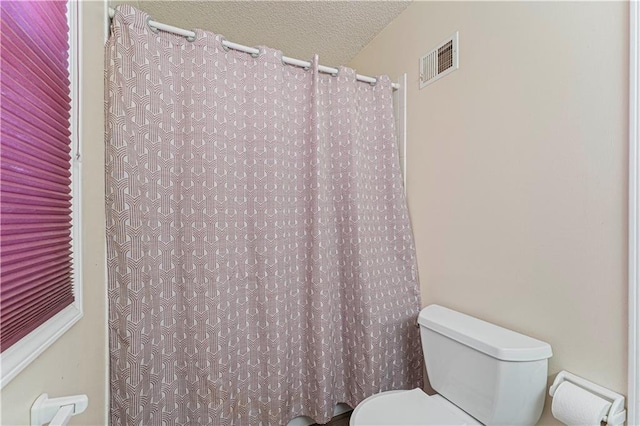 bathroom with curtained shower, toilet, visible vents, and a textured ceiling