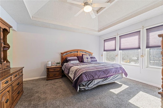 bedroom featuring dark carpet, a textured ceiling, a raised ceiling, and baseboards