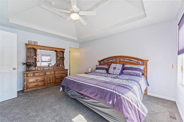 carpeted bedroom featuring visible vents, ceiling fan, baseboards, and a tray ceiling