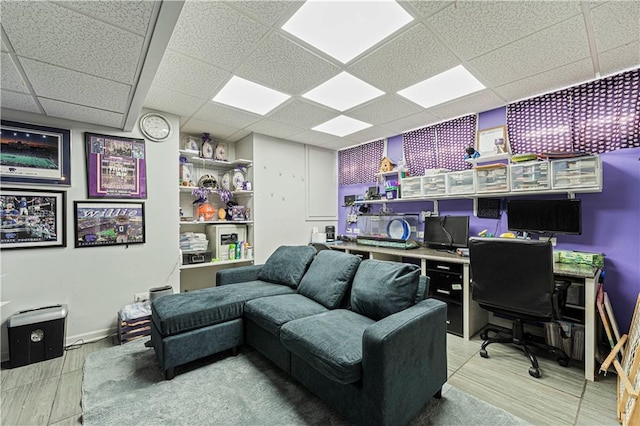 office area with a drop ceiling, baseboards, and wood finished floors