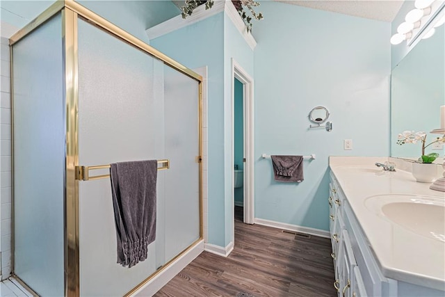 full bath with double vanity, wood finished floors, a stall shower, and a sink