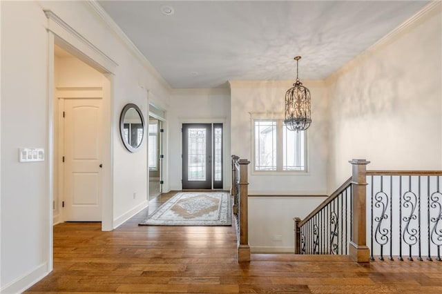 foyer entrance featuring an inviting chandelier, crown molding, and wood-type flooring