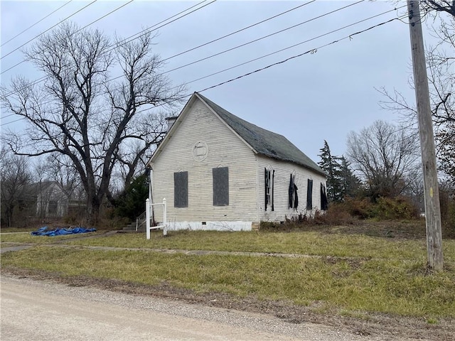 view of side of property with crawl space and a lawn