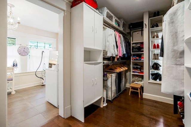 spacious closet featuring an inviting chandelier, washer / clothes dryer, and wood-type flooring