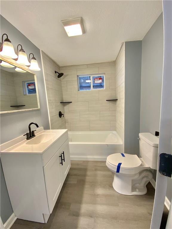 full bathroom featuring vanity, tiled shower / bath, hardwood / wood-style flooring, and toilet