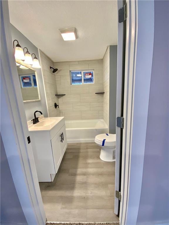 full bathroom featuring vanity, tiled shower / bath, wood-type flooring, and toilet