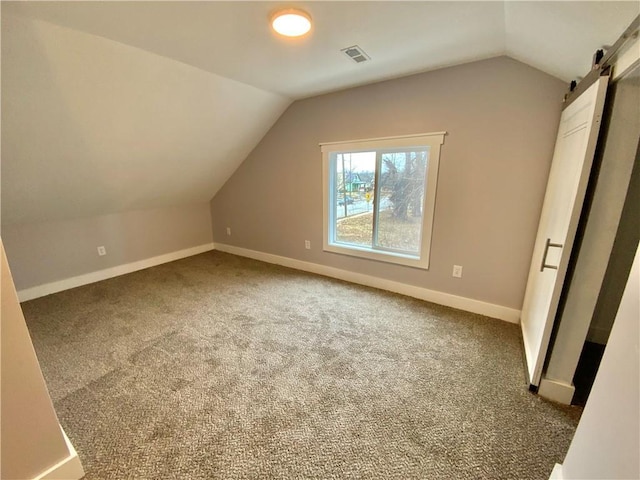 additional living space featuring lofted ceiling, a barn door, and carpet floors