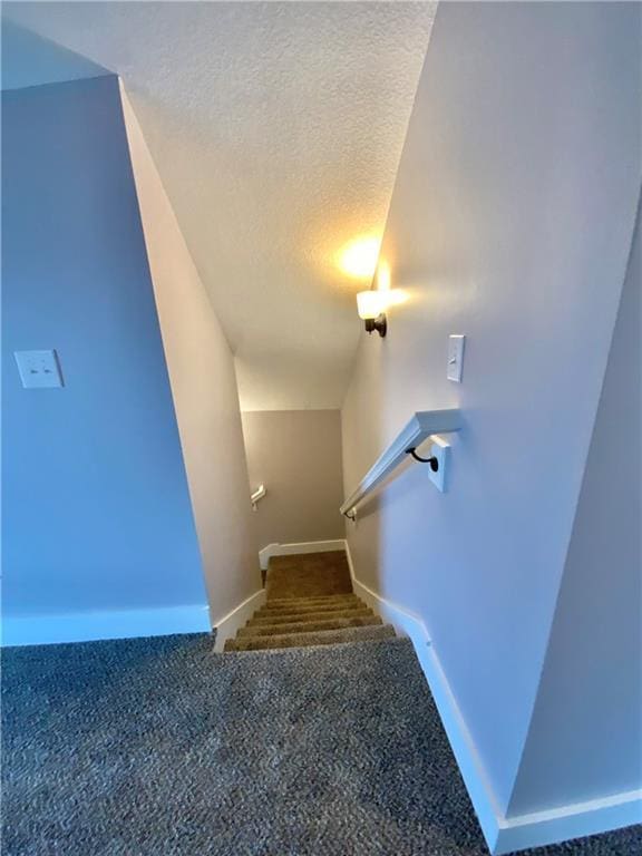 staircase featuring carpet and a textured ceiling