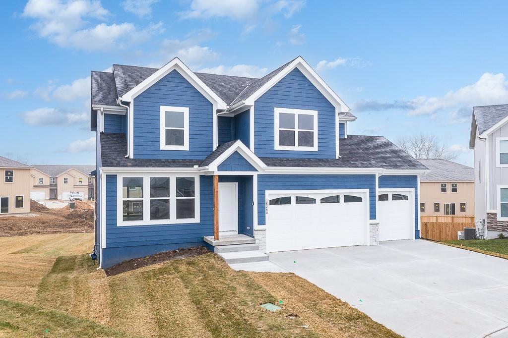 view of front of home featuring a garage, cooling unit, and a front lawn